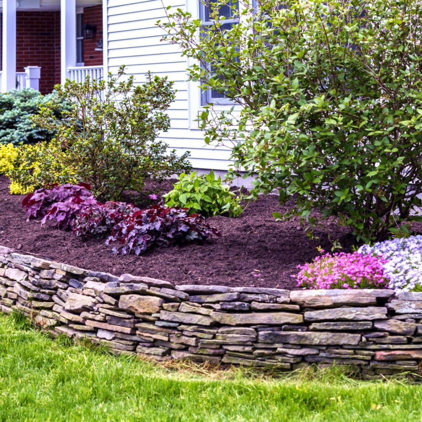Stunning landscape design by Arellano Landscaping showcasing lush greenery, vibrant seasonal flowers, and expert hardscaping elements in a residential St. Charles, IL property.