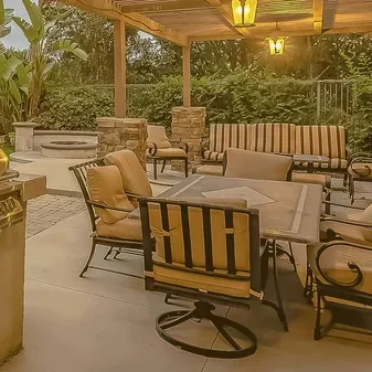 Custom outdoor kitchen installation by Arellano Landscaping featuring natural stone countertops, built-in grill, stainless steel appliances, and covered pergola creating the ultimate backyard entertaining space in Geneva